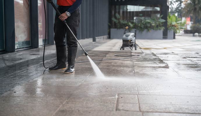 A person is power washing oily floor