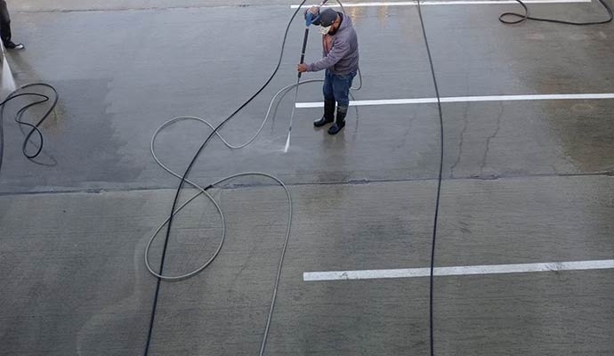 A person power washing a parking lot