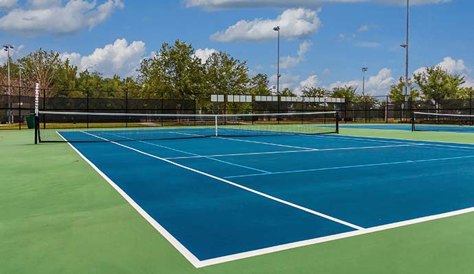 Clean blue and green outdoor tennis court with net under clear sky
