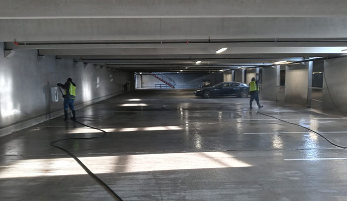 Cleaning crew using pressure washers to clean an indoor parking garage