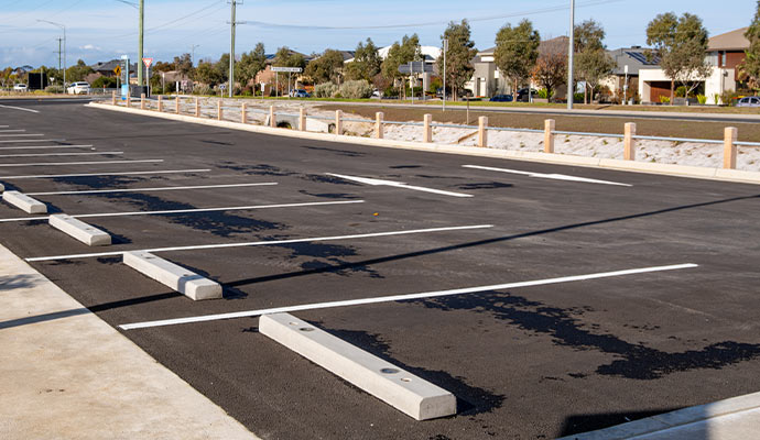 Commercial parking lot with concrete wheel stops painted parking lines and newly paved asphalt surface