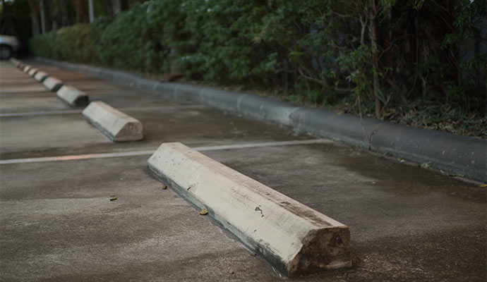 Concrete parking wheel stops installed in outdoor parking lot
