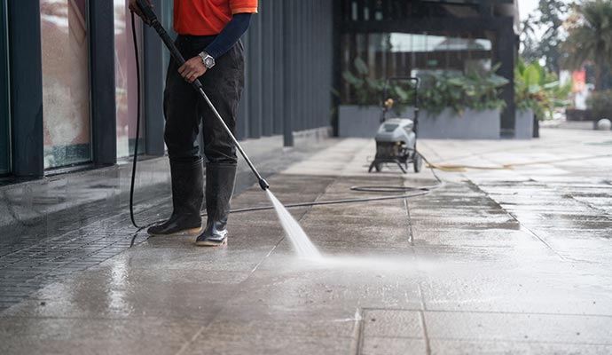 A person is power washing concrete surface