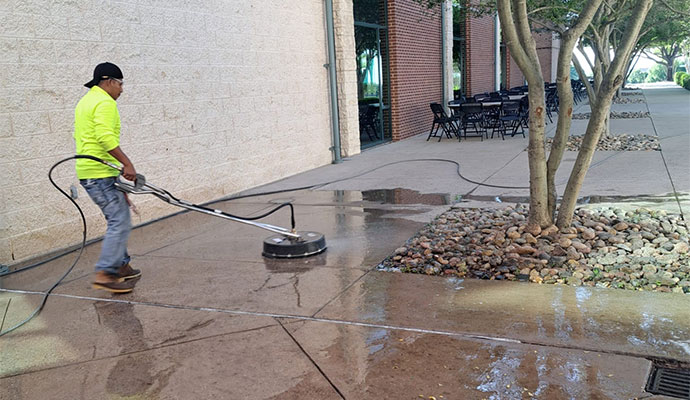 Expert cleaning a concrete sidewalk using a professional pressure washer