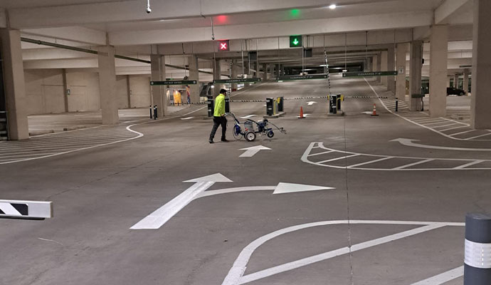 Indoor parking garage with freshly painted directional arrows lane markings and pavement striping layout