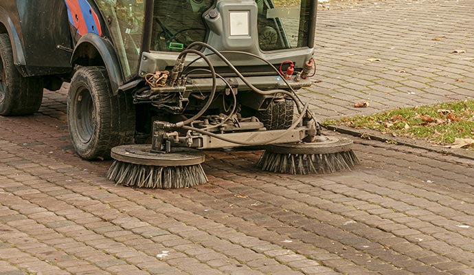 Mechanical pavement machine sweeping dirt and debris from road