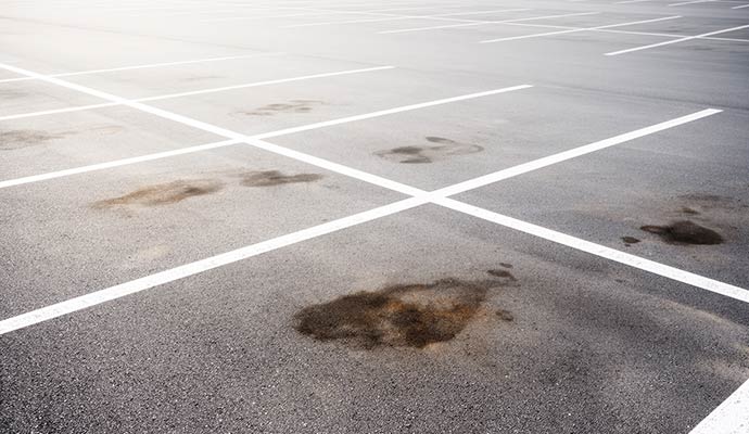 Multiple dark oil stains on parking-lot surface