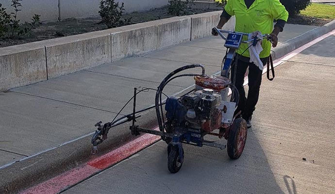 Commercial striping professional applying fresh paint to a curb