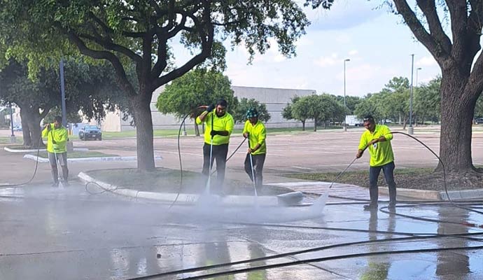 Professional team pressure washing a concrete parking area
