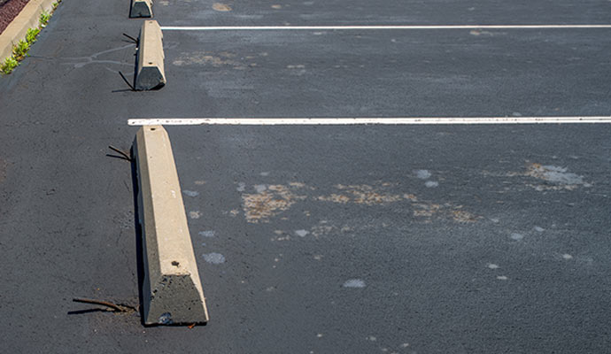 Concrete wheel stops installed in asphalt parking lot with painted commercial parking space lines