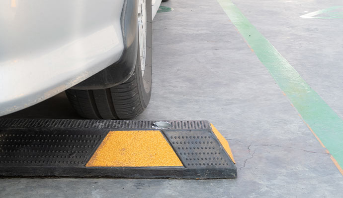 Vehicle parked against rubber parking lot wheel stop on commercial concrete parking surface