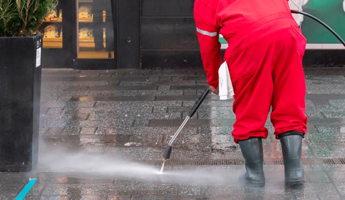 Expert worker power washing a commercial building entryway