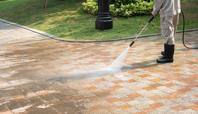 Professional worker pressure washing sidewalk