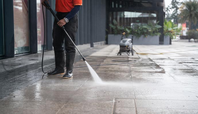 Professional worker pressure washing a walkway