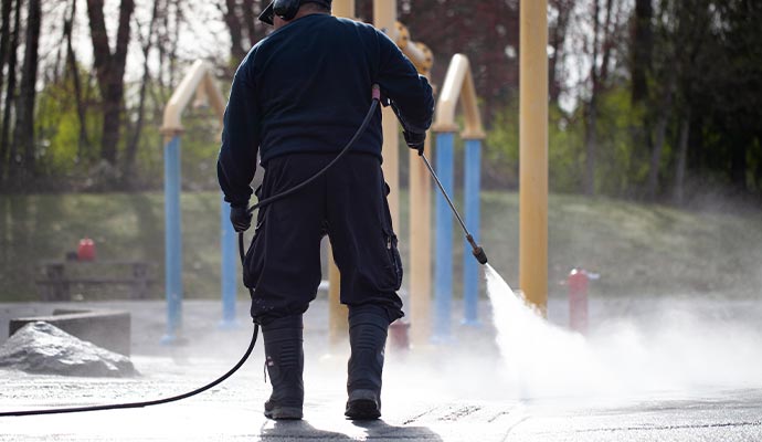 Worker pressure washing a playground