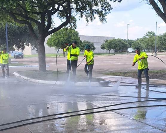 Professional team pressure washing a concrete parking area