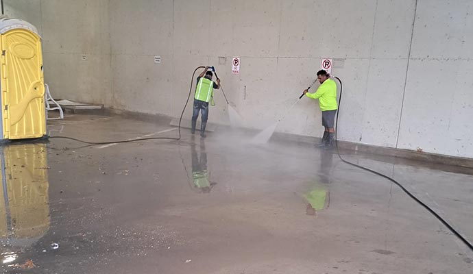 Two people are power washing a garage